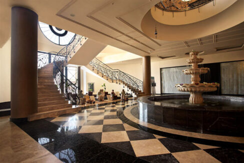 black and white checkboard flooring with black fountain and staircase