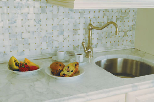 kitchen sink with green square tile back splash and muffins