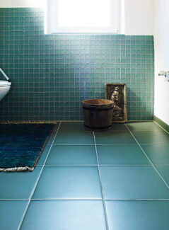 large blue square tile on bathroom floor with smaller blue tile on wall