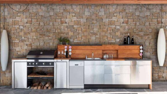 backyard barbeque area with brick wall behind it and stainless steel appliances