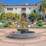 blue and gold tile fountain in backyard in front of Spanish style house